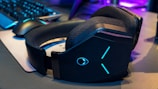 A sleek gaming headset with neon blue lights on a black desk