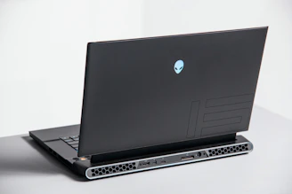 A sleek gaming laptop glowing with blue accents on a dark futuristic surface