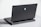 A sleek, dark laptop with a futuristic design, showcasing a blue alienware logo on its back cover. The laptop has a robust hinge, visible ventilation slots, and several ports at the back. It's placed on a light gray surface, with part of the slightly open keyboard in view.