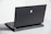 A sleek, dark laptop with a futuristic design, showcasing a blue alienware logo on its back cover. The laptop has a robust hinge, visible ventilation slots, and several ports at the back. It's placed on a light gray surface, with part of the slightly open keyboard in view.