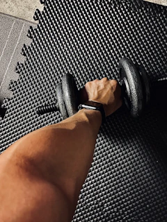 person wearing black and white shirt holding black dumbbell