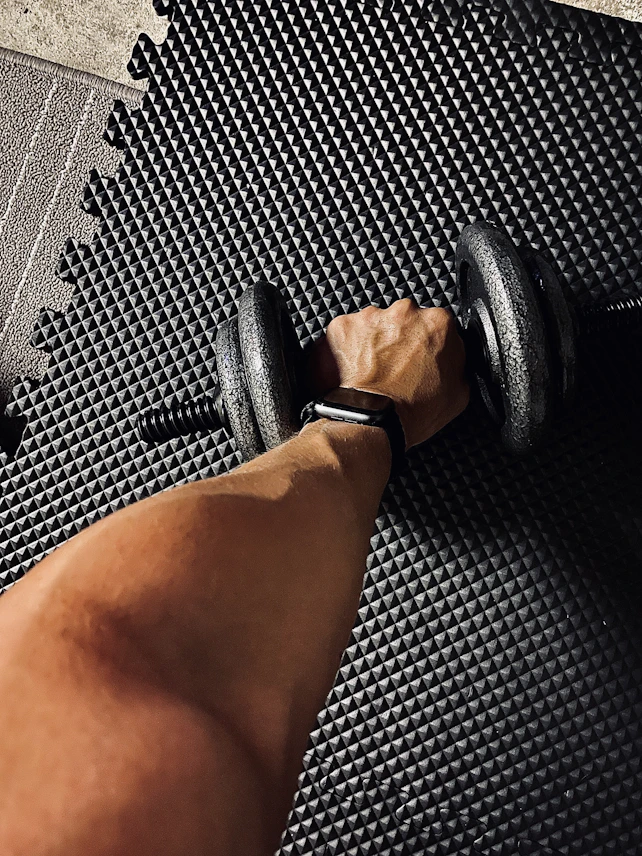 person wearing black and white shirt holding black dumbbell