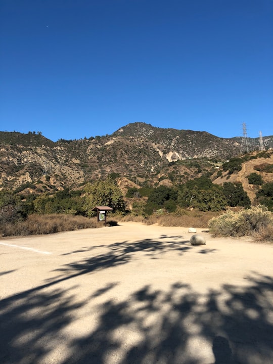 brown wooden bench on brown sand near green mountain under blue sky during daytime in Eaton Canyon Nature Center United States