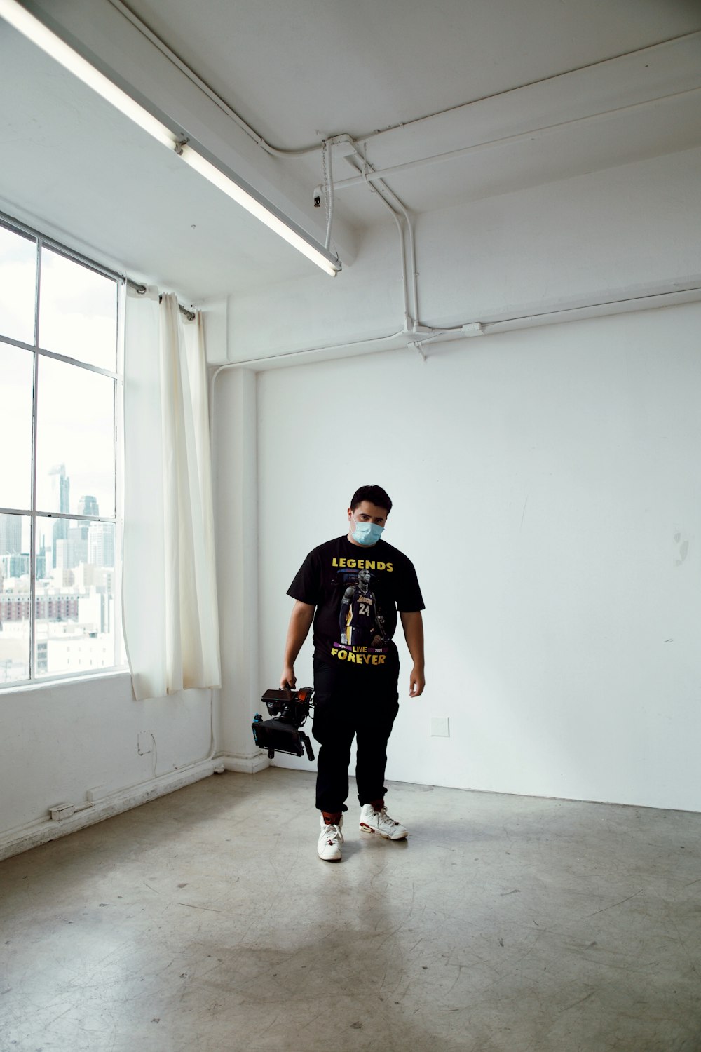 man in black crew neck t-shirt and black pants standing on gray concrete floor