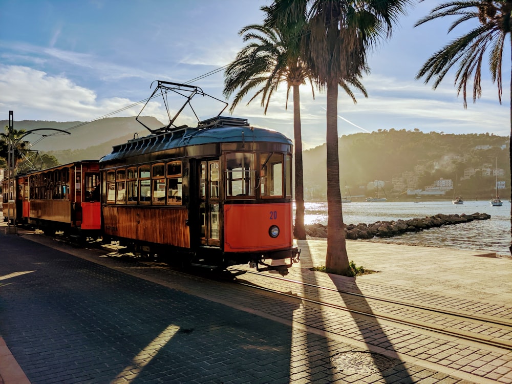 red and white train on rail road near body of water during daytime