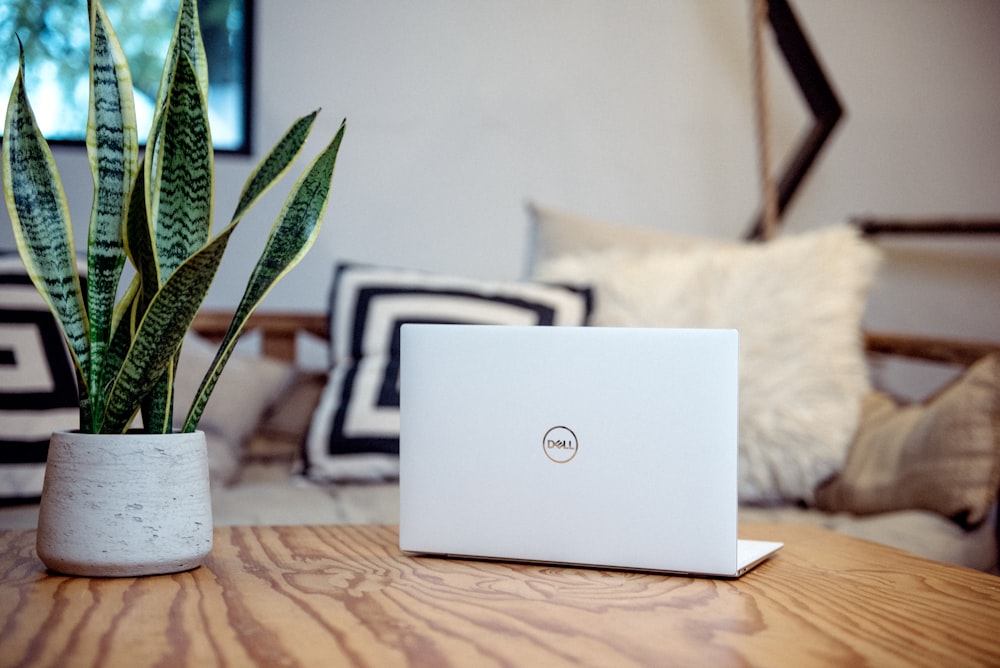 silver laptop on brown wooden table