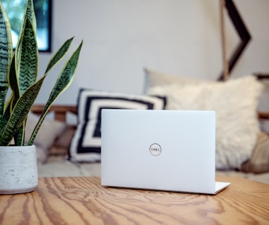 silver laptop on brown wooden table