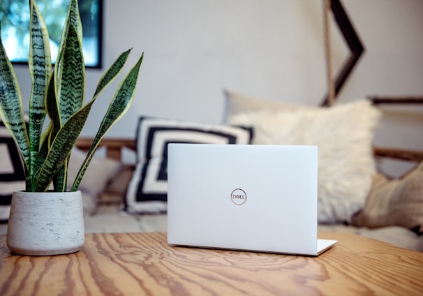 silver laptop on brown wooden table