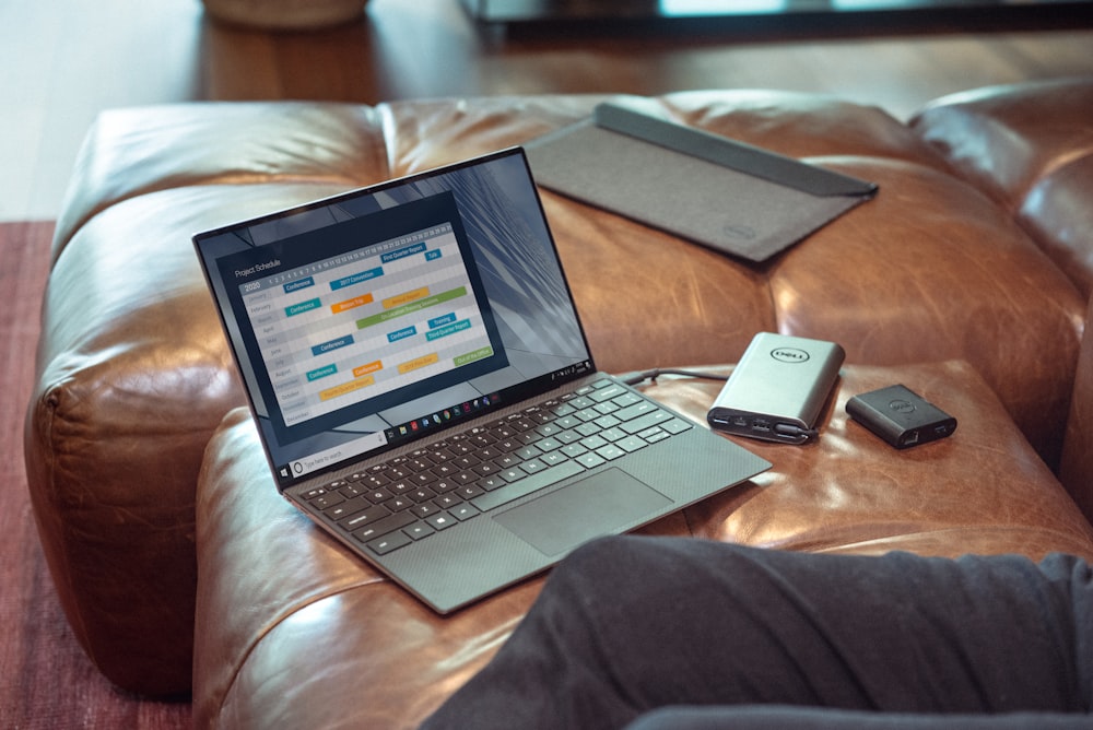 black and gray laptop computer on brown leather couch