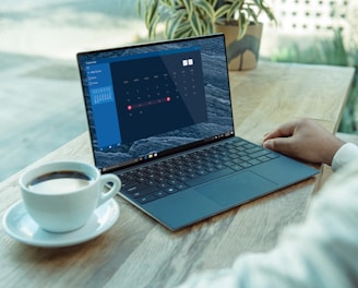 person using black laptop computer on brown wooden table