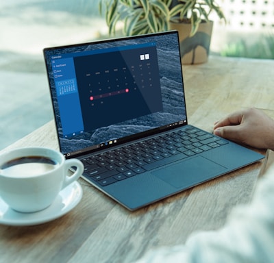 person using black laptop computer on brown wooden table