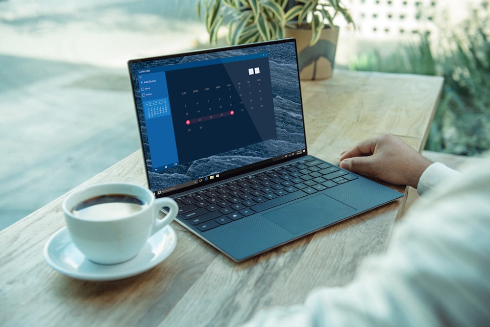 person using black laptop computer on brown wooden table