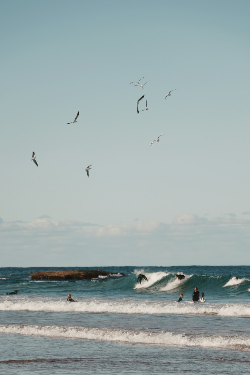 persone che fanno surf sulle onde del mare durante il giorno