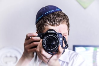 man in blue knit cap holding black and silver nikon dslr camera