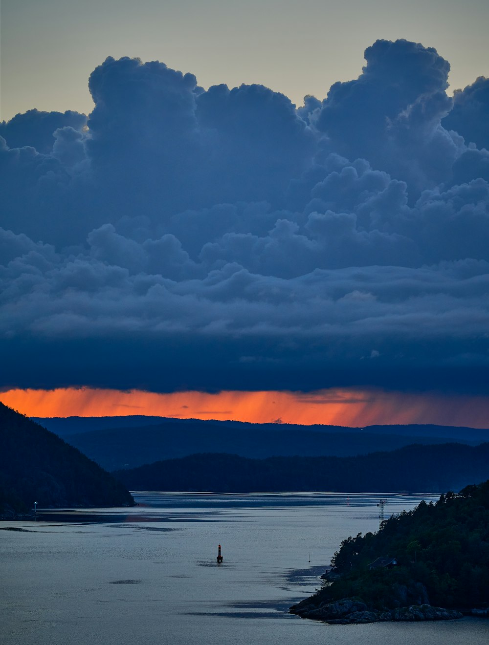 body of water near mountain during sunset