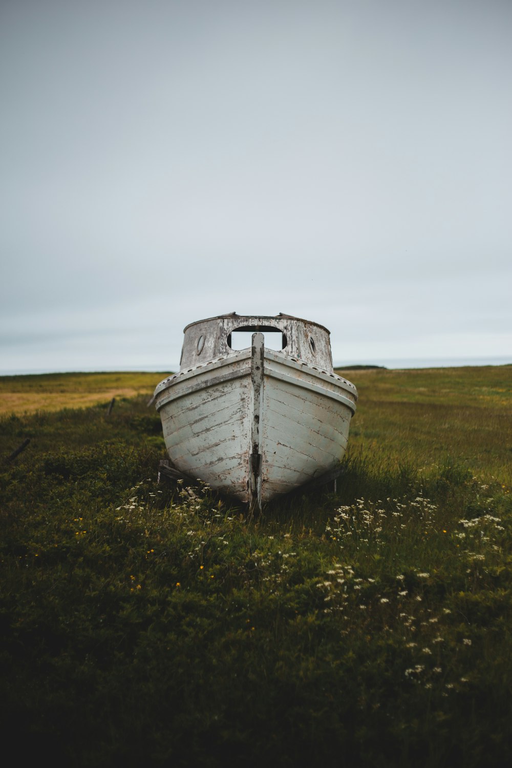 white and brown boat on green grass field under white sky during daytime