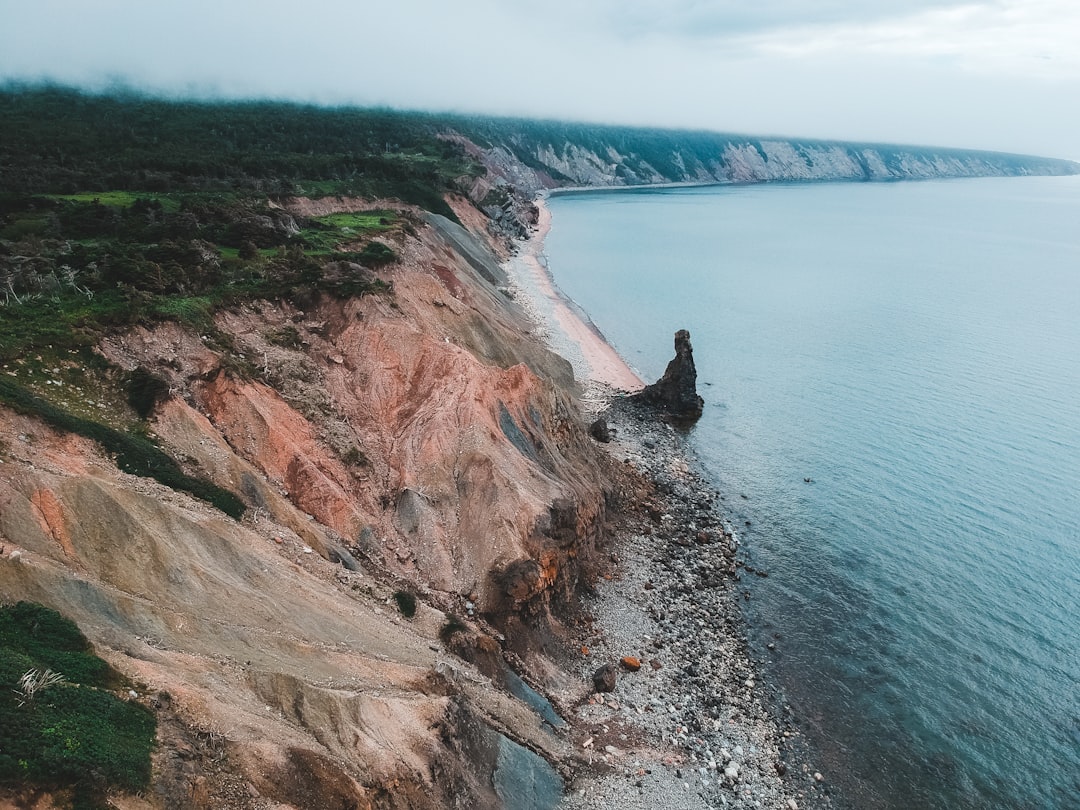 person sitting on rock formation near body of water during daytime