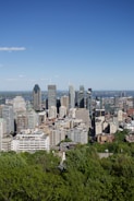 Drone view of a vibrant city skyline with skyscrapers under a clear blue sky.