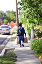 A friendly assistant carrying grocery bags with a smile in a neighborhood setting.