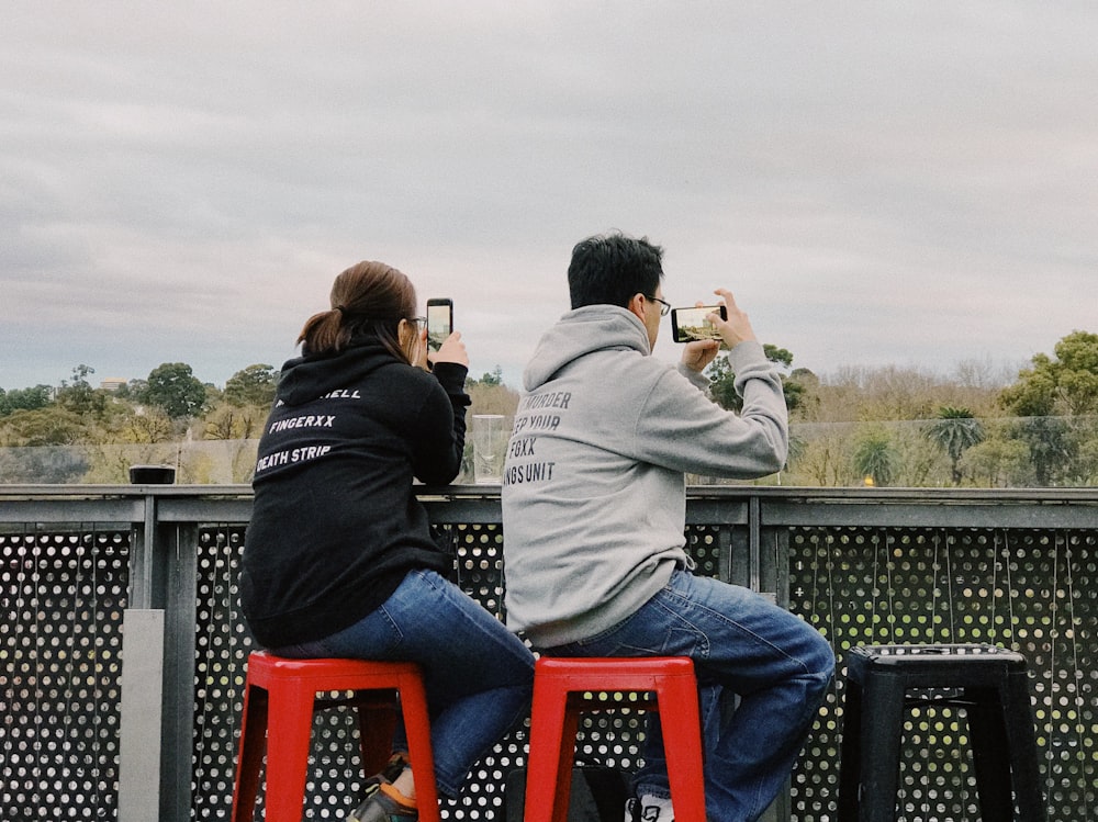 man and woman sitting on black metal bench during daytime