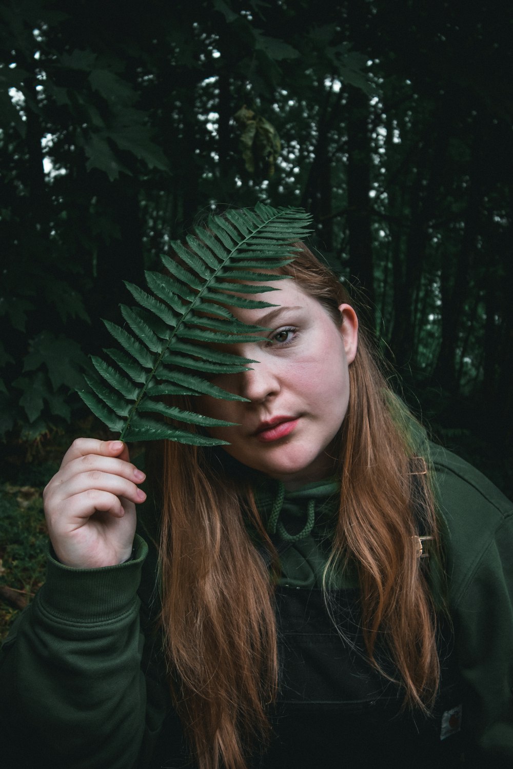 woman in green jacket holding green leaf