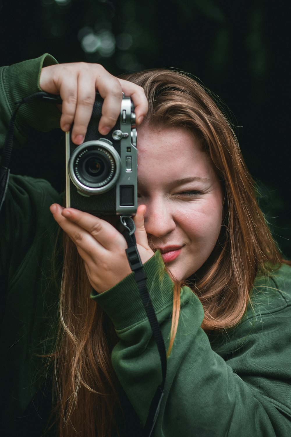 woman in green jacket holding gray and black camera