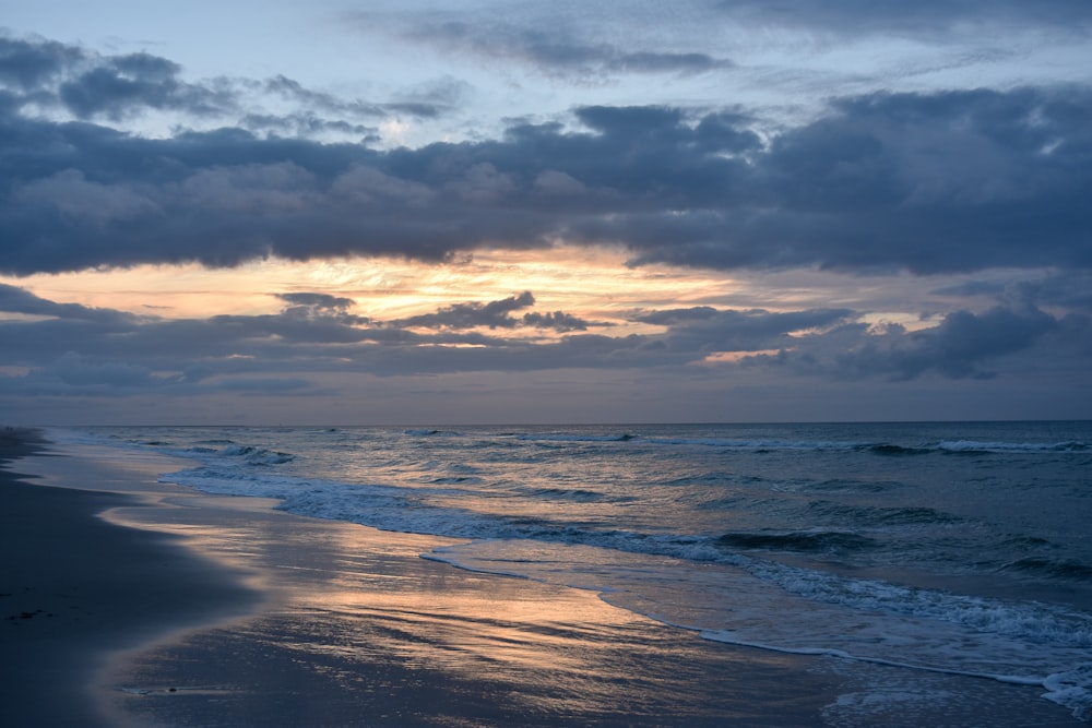 sea waves crashing on shore during sunset