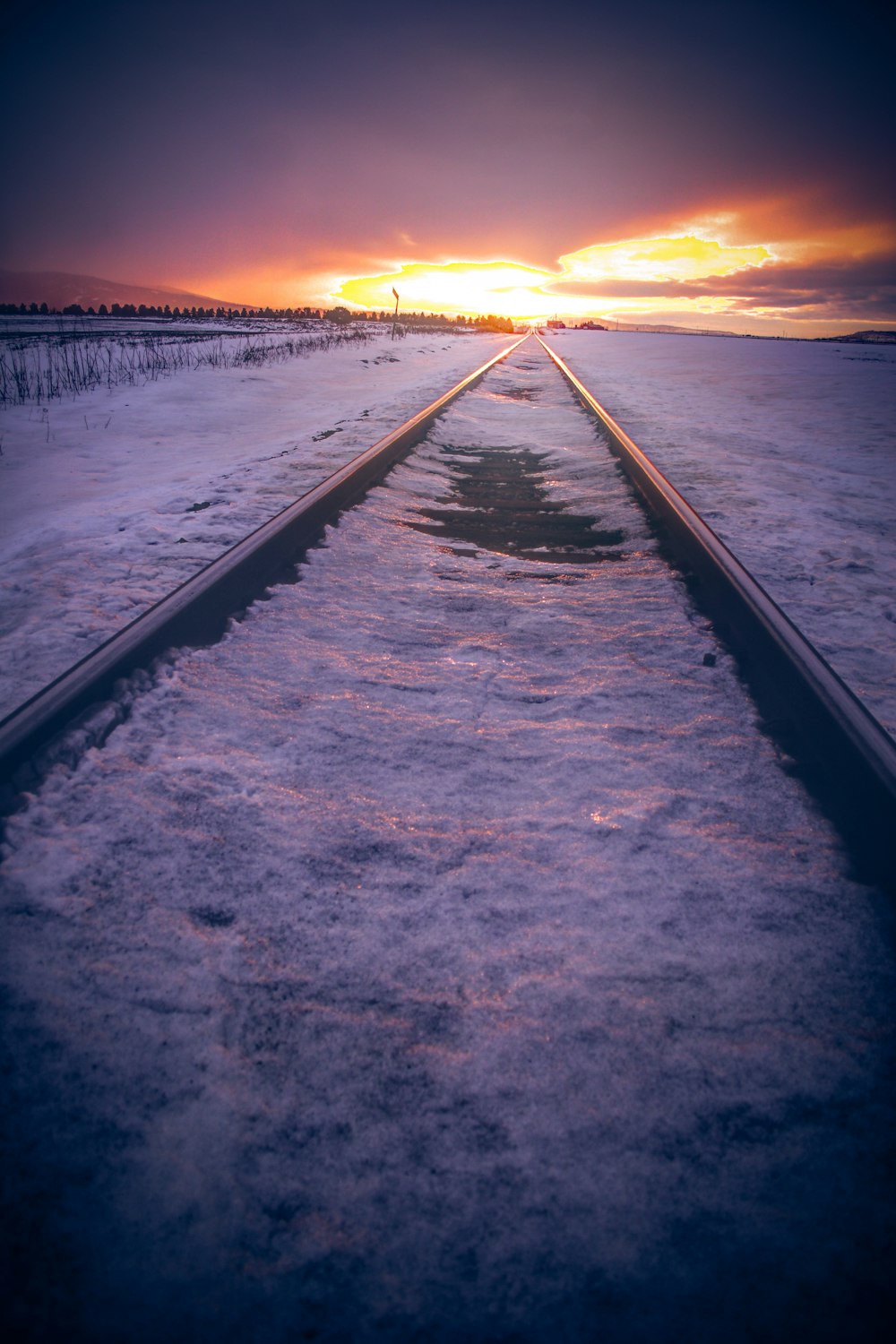 black metal railings on snow covered ground during sunset