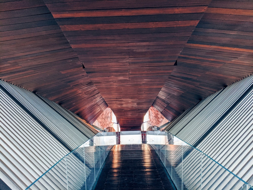 man in white shirt walking on brown wooden tunnel