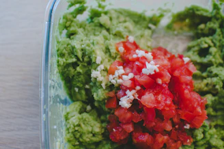 Avocado-infused mojo verde in a small bowl surrounded by ripe avocados and herbs.