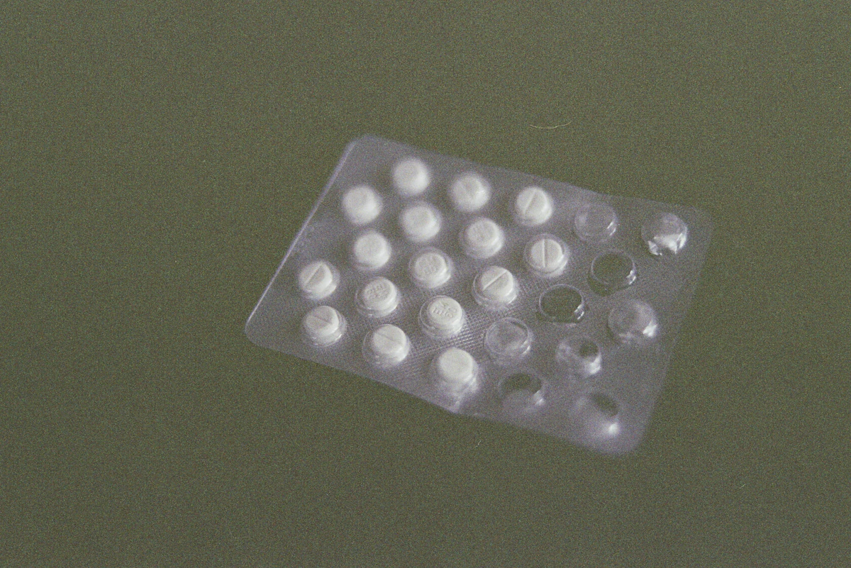 Scattered psychotropic tablets in low light, representing the misuse of antipsychotic and sedative drugs as chemical restraints