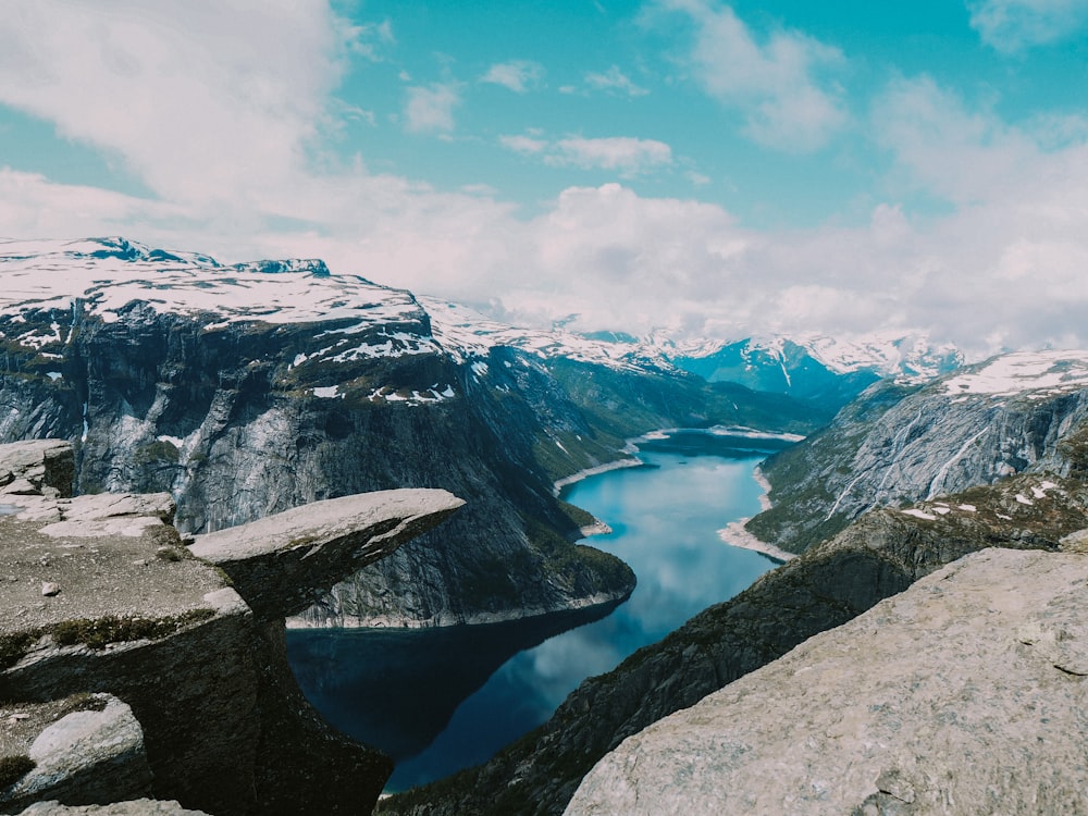 body of water between rocky mountains under blue sky during daytime