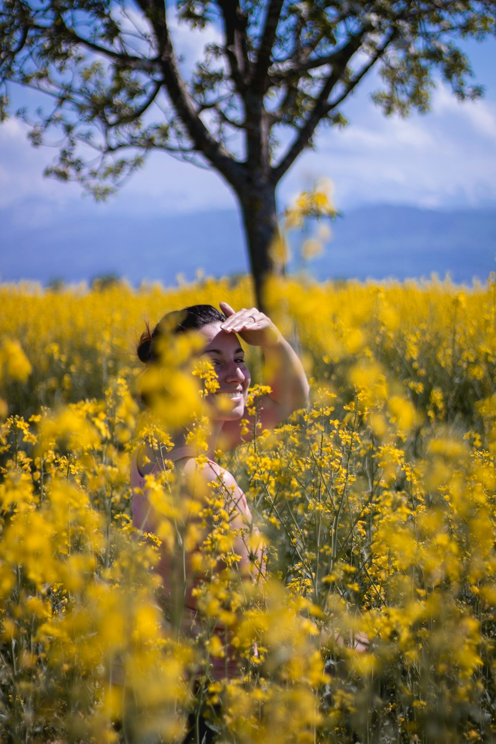 woman in white and black stripe long sleeve shirt standing on yellow flower field during daytime