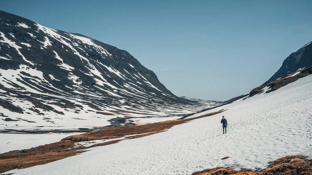 person walking on white sand near snow covered mountain during daytime