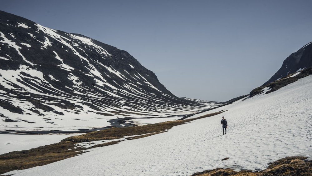 person walking on white sand near snow covered mountain during daytime