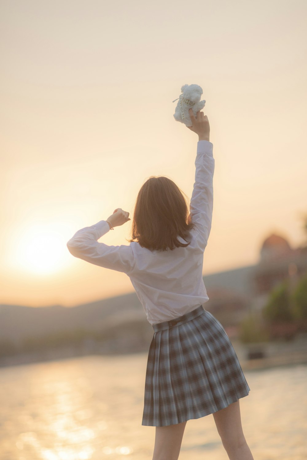 girl in white long sleeve shirt and blue and white plaid skirt holding white cotton candy