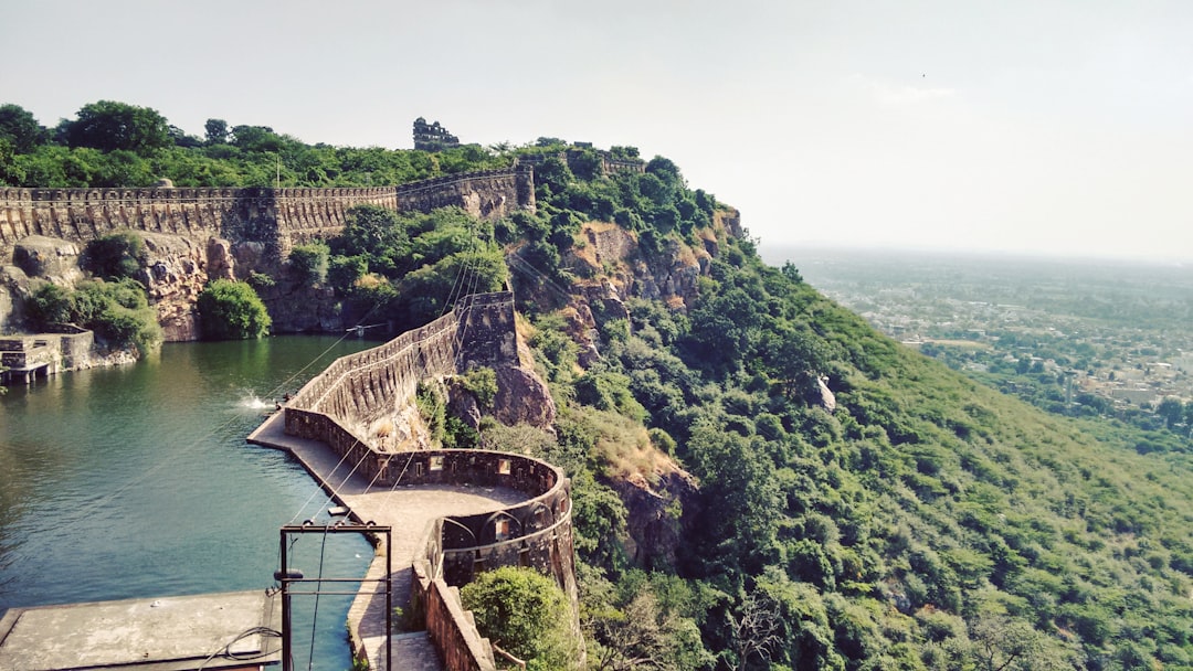 green and brown mountain near body of water during daytime in Chittorgarh Fort India