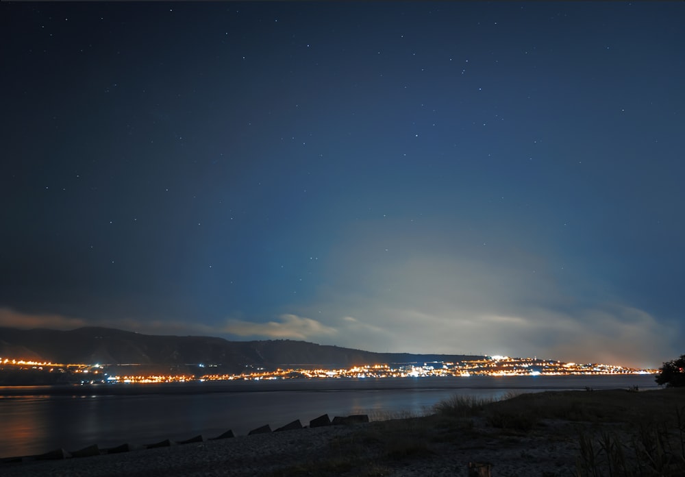 body of water near mountain during night time