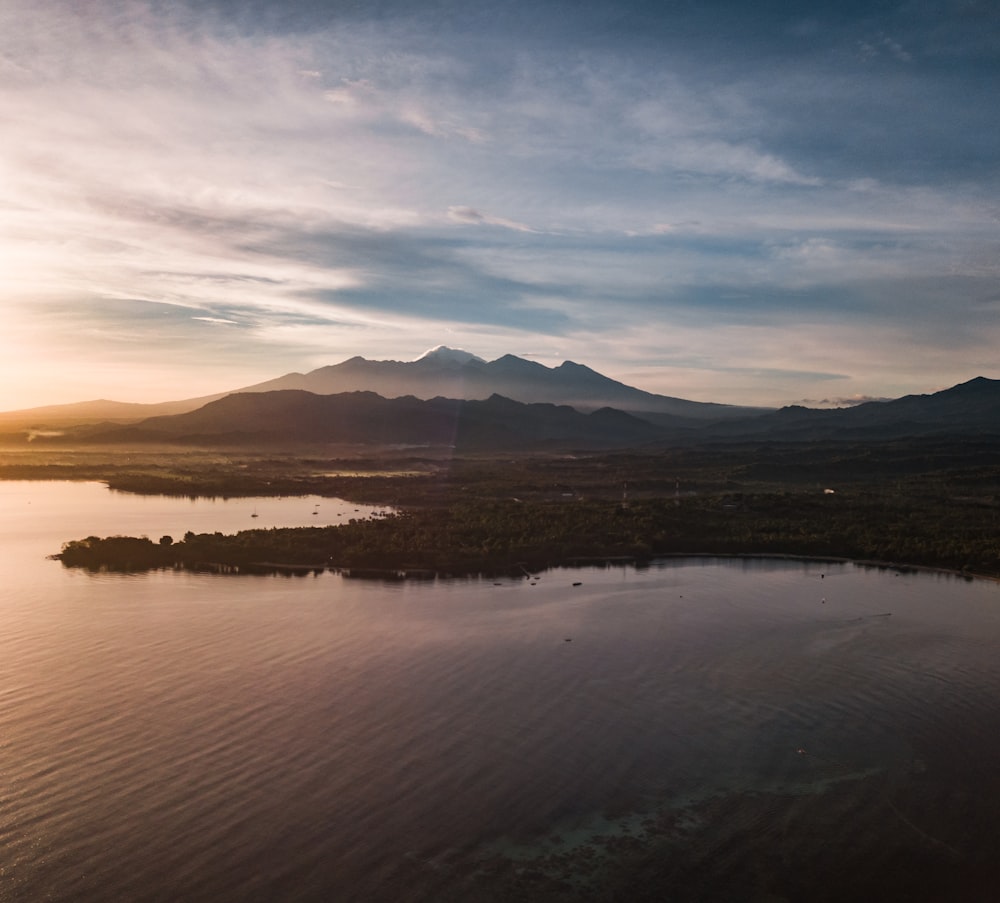 body of water near mountain during sunset