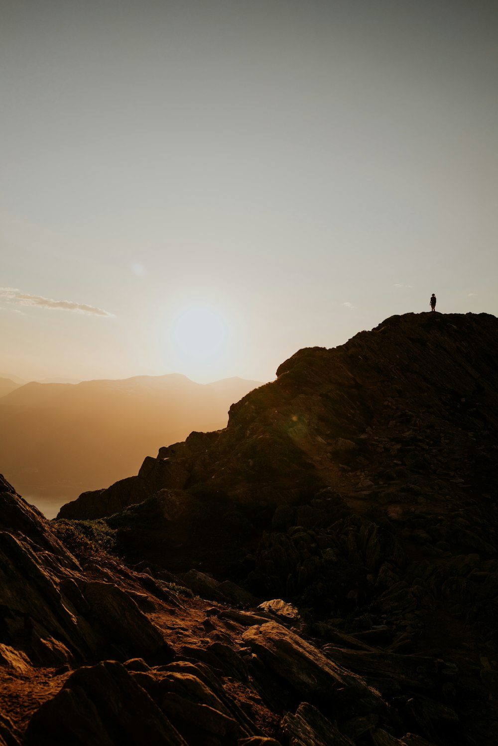 Silueta de la persona de pie en la formación rocosa durante la puesta del sol