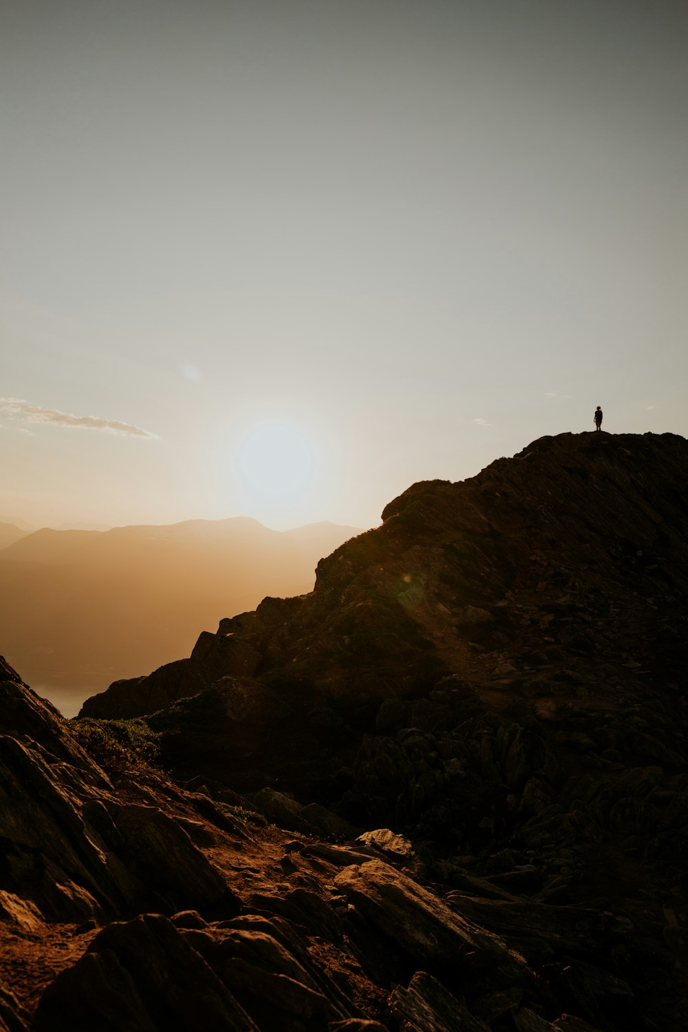 silhouette of person standing on rock formation during sunset