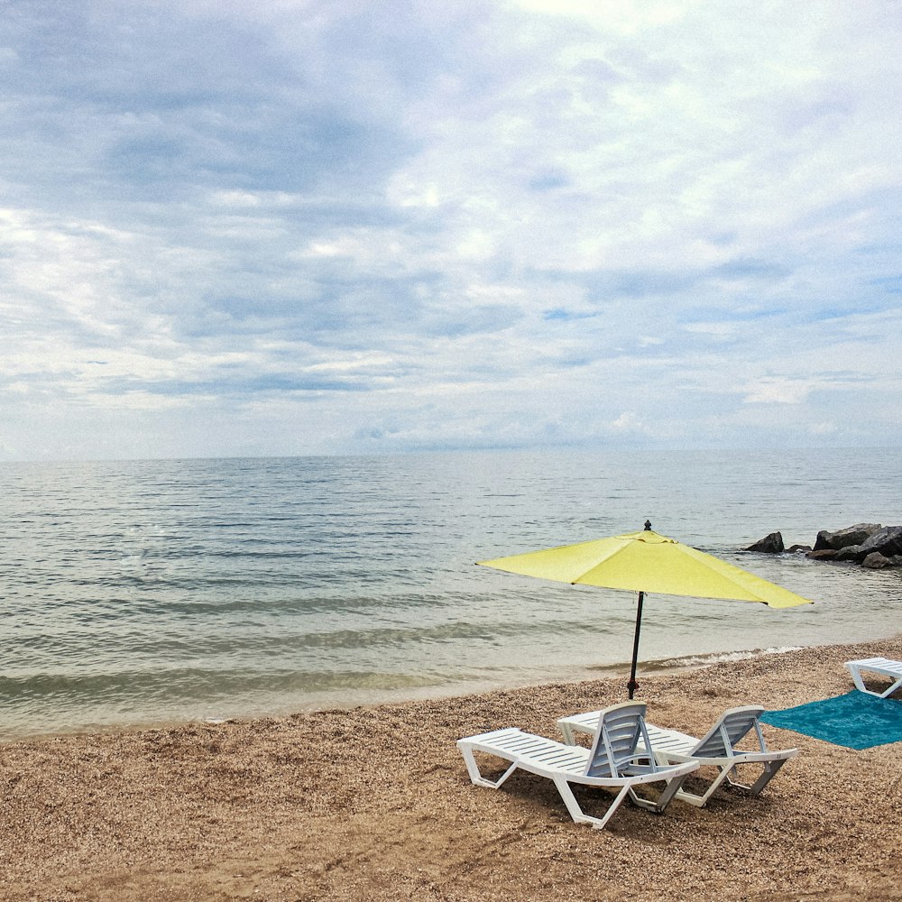 sedia a sdraio bianca e blu sulla spiaggia durante il giorno