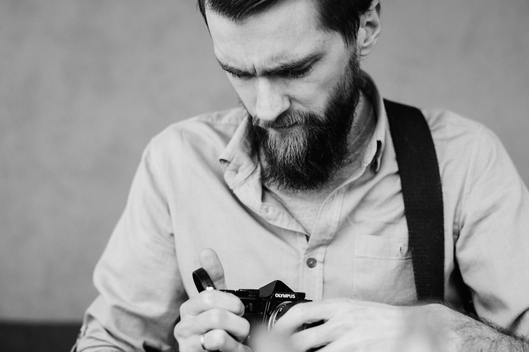 man in white dress shirt holding black dslr camera