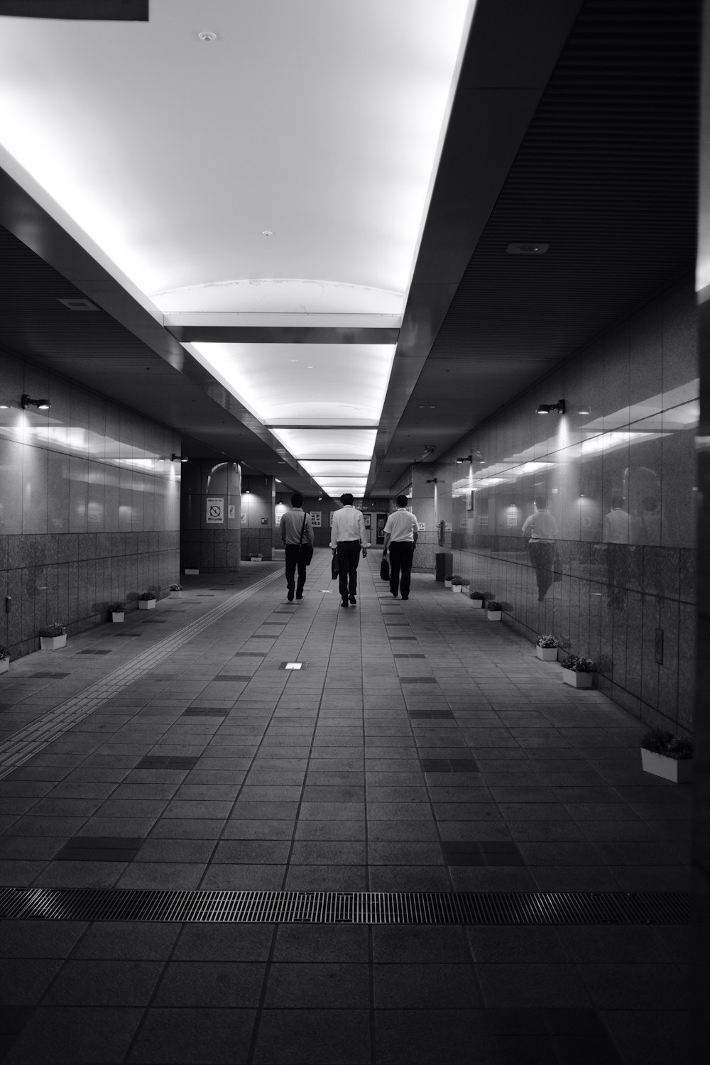 grayscale photo of people walking on hallway