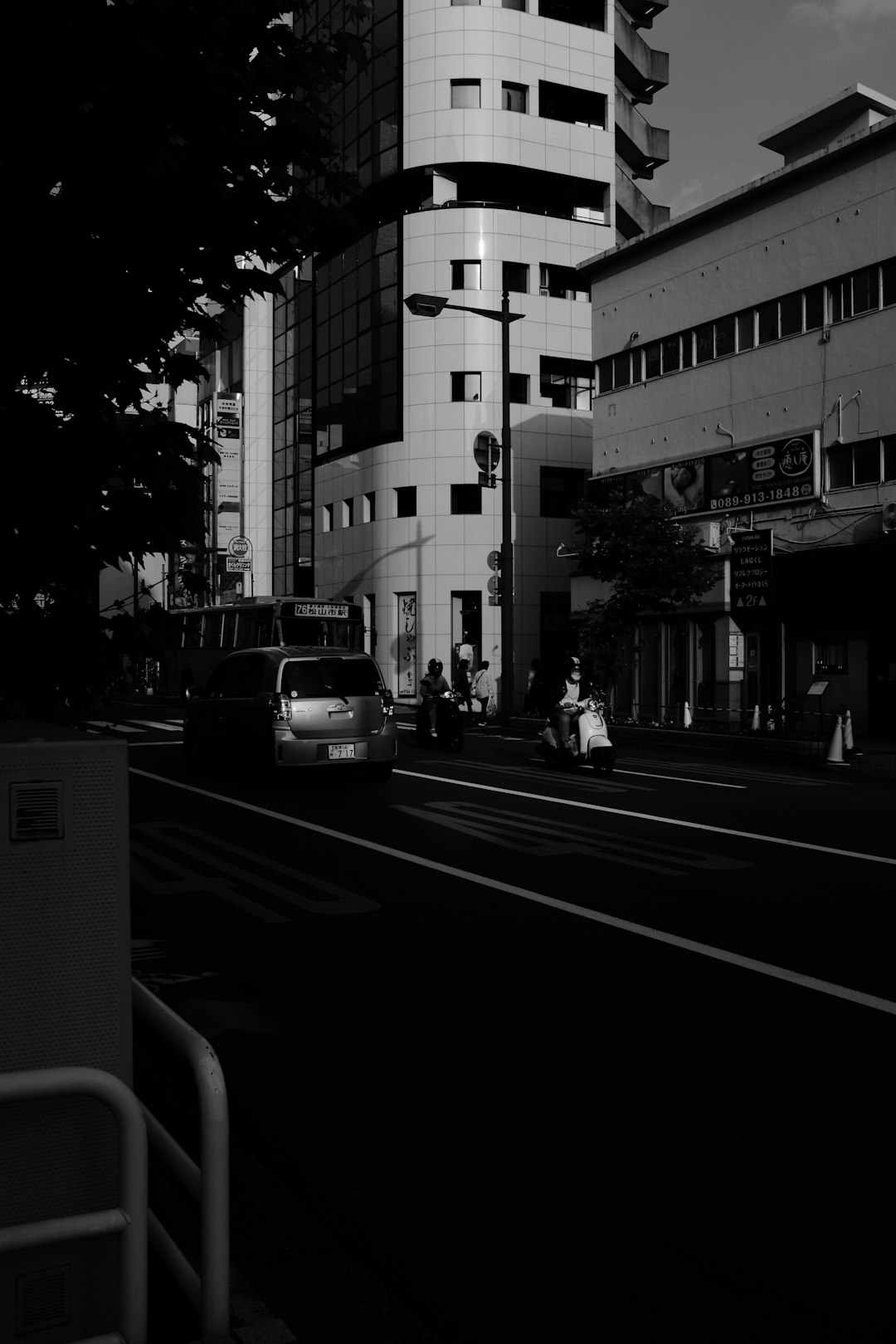 grayscale photo of man riding bicycle on road near building