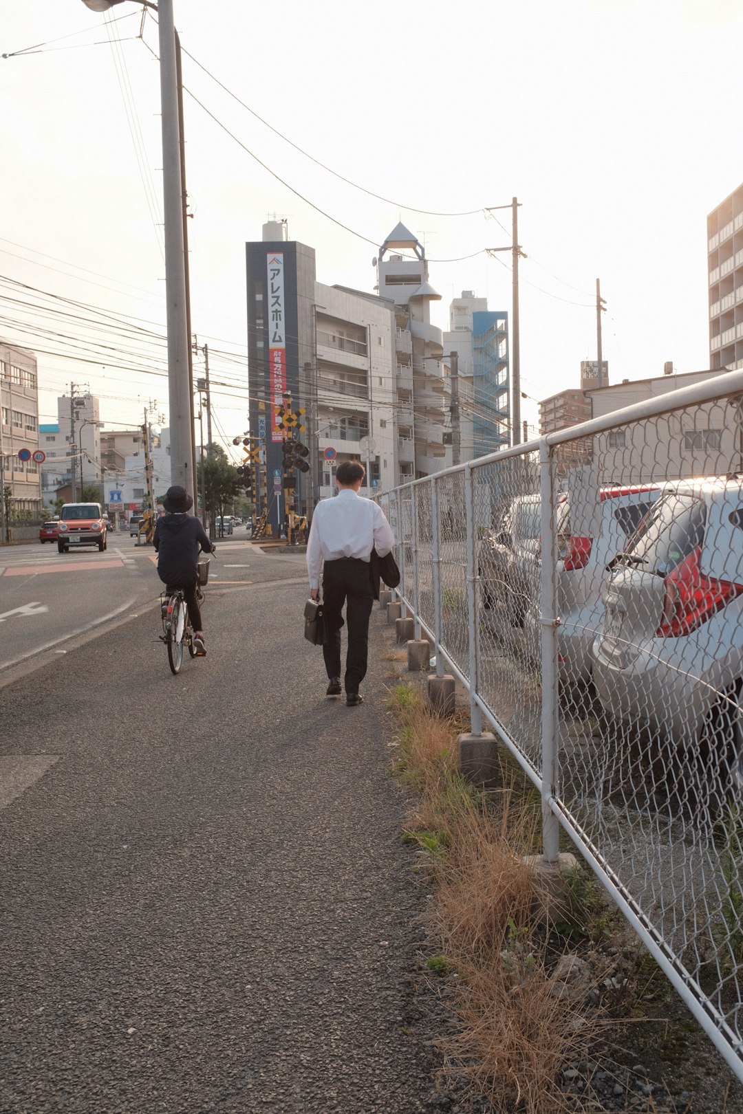 man in white jacket riding bicycle on road during daytime