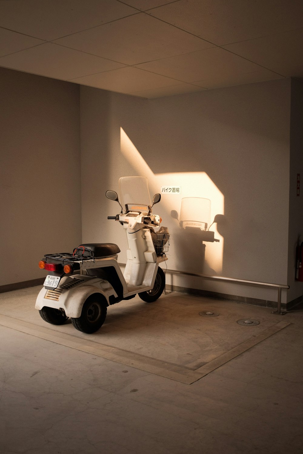 white and black motor scooter parked beside white wall