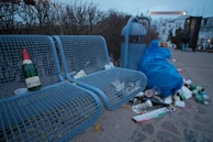 A public park with broken benches and overflowing trash bins, illustrating municipal neglect.