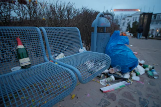 Urban street scene featuring recycled plastic benches surrounded by green plants and industrial recycling bins