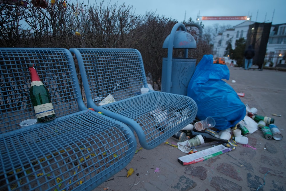 Persona con chaqueta azul y jeans de mezclilla azules sentada en un banco de metal blanco durante el día